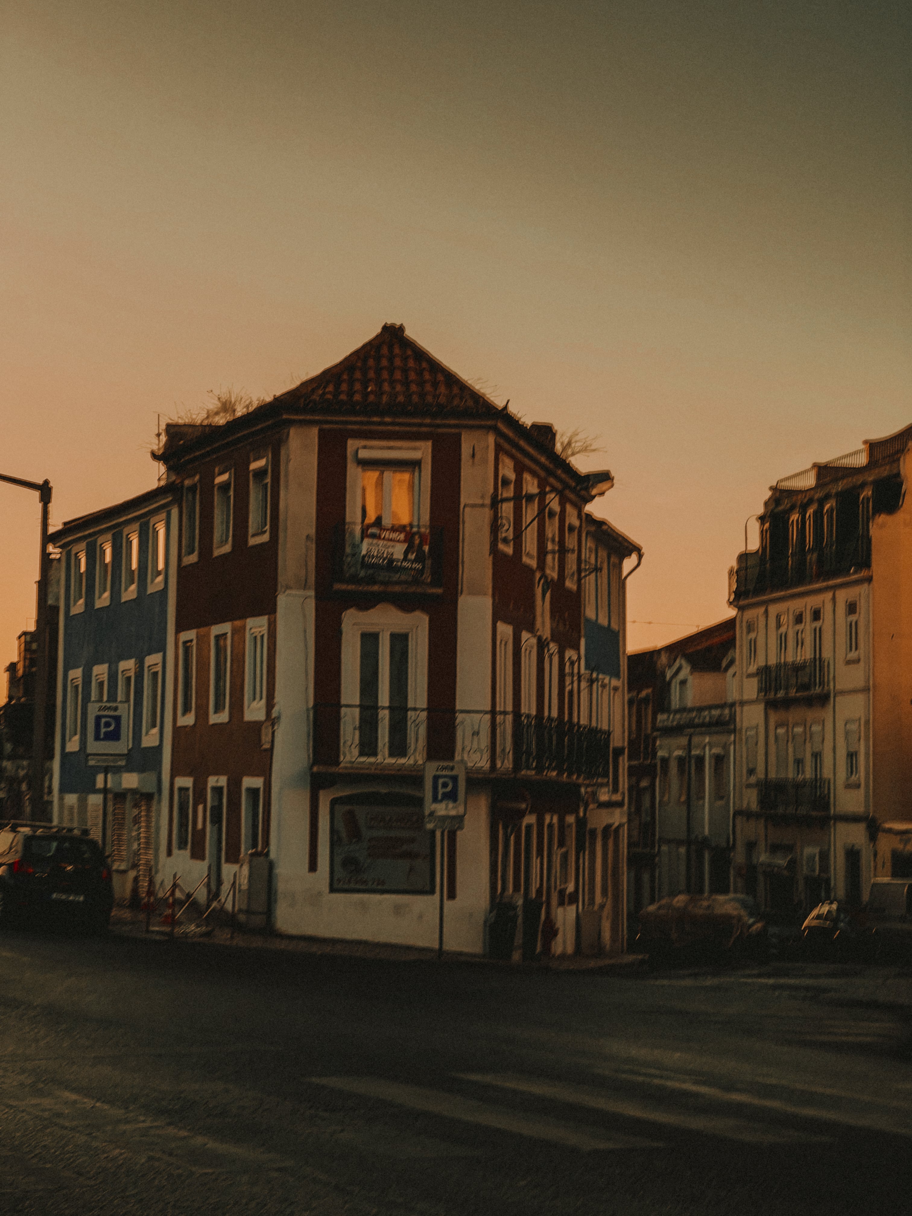 Corner building with lit window against pink sunset sky — Graça, Lisbon