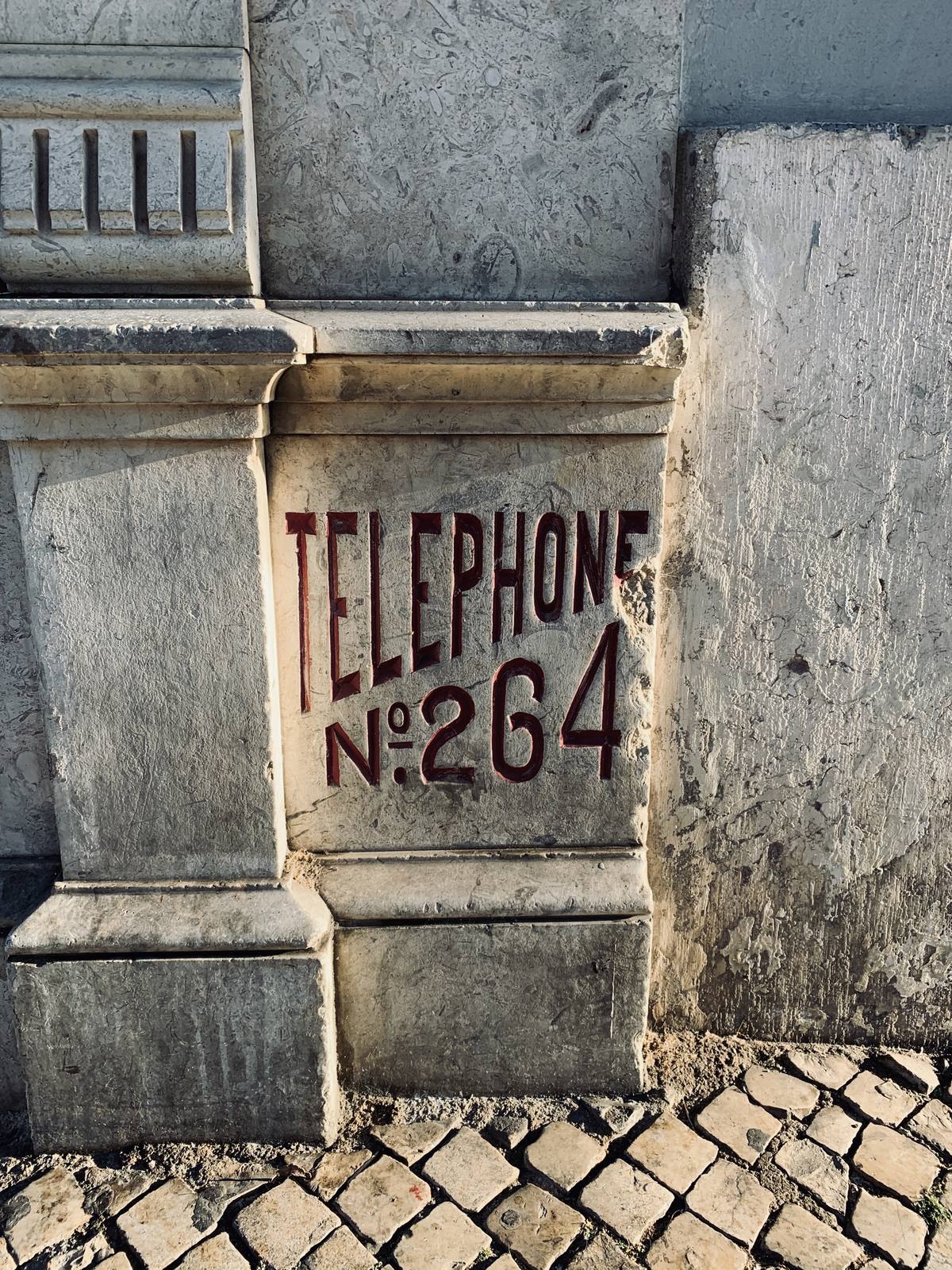 No. 264, Carved In Stone, Príncipe Real, Lisbon — Raking warm light on carved stone inscription — graphic, deliberate, typographic; cobblestones ground it in Lisbon; no clutter, no people, prints clea